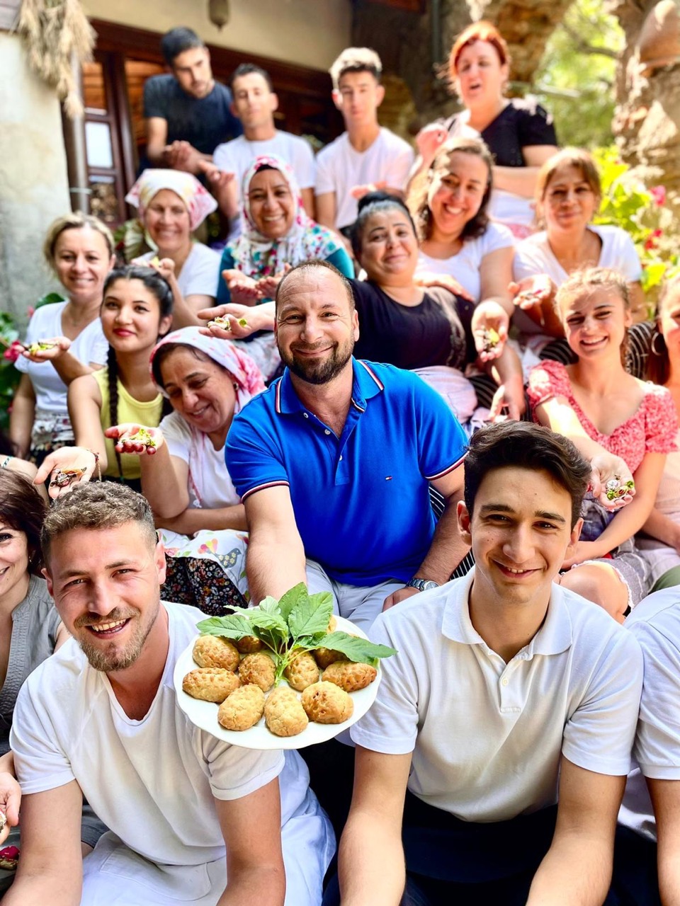 The hotel staff on the stone steps, holding a plate of pastries